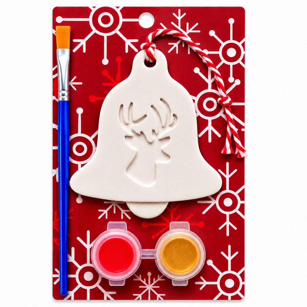 A Christmas ornament plaster painting kit on a red card with white snowflake patterns. The kit includes a white plaster bell-shaped ornament with a reindeer silhouette cutout, a blue-handled paintbrush, two small paint pots with red and yellow paint, and a red-and-white striped hanging string.