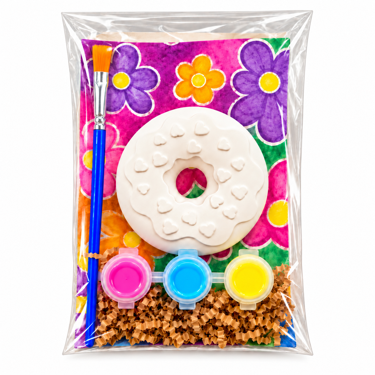 A packaged DIY plaster paint kit containing a white donut-shaped object, a blue paintbrush, three small paint pots in pink, blue, and yellow, and a colorful floral backing card, all sealed in a clear plastic bag.