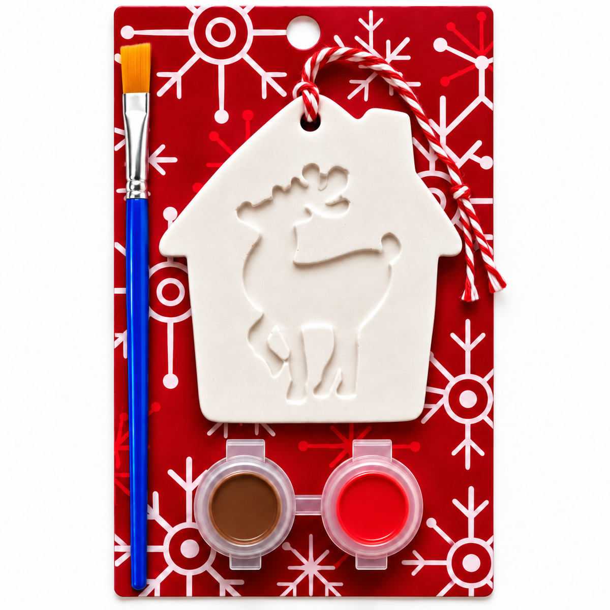 A Christmas ornament plaster painting kit in a red carded package with snowflake patterns. The kit includes a white house-shaped plaster ornament with a reindeer cutout, a blue-handled paintbrush with orange bristles, and two small paint pots containing brown and red colors.