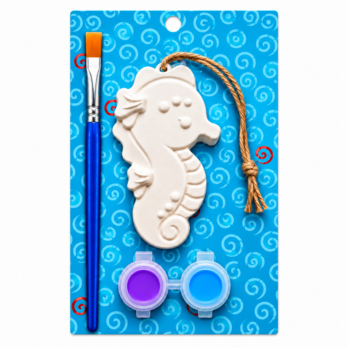 Seahorse plaster paint kit on a blue card with swirl patterns. The kit includes a white seahorse-shaped plaster with a hanging string, a blue-handled paintbrush with an orange bristle, and two small paint pots with purple and blue paint.