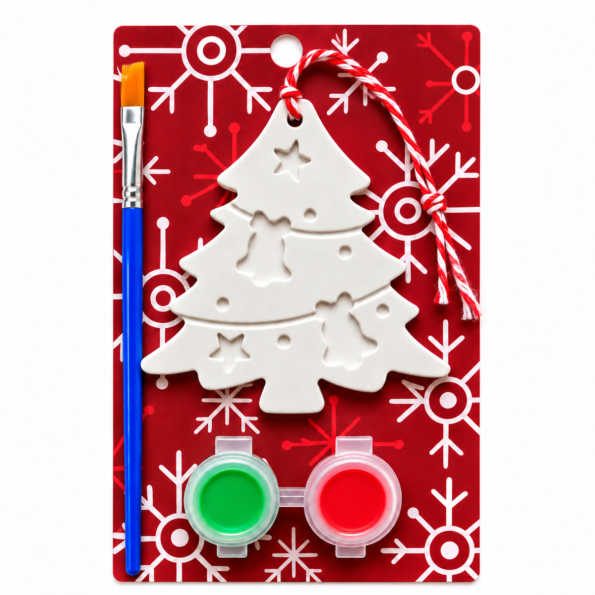 A Christmas tree craft kit in retail packaging, featuring a white plaster tree ornament, a blue paintbrush, and two small paint pots in green and red, all mounted on a red card with white snowflake patterns.