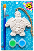 Plaster sea turtle ornament with hanging twine, green and blue paints and a paintbrush on a blue swirl background.